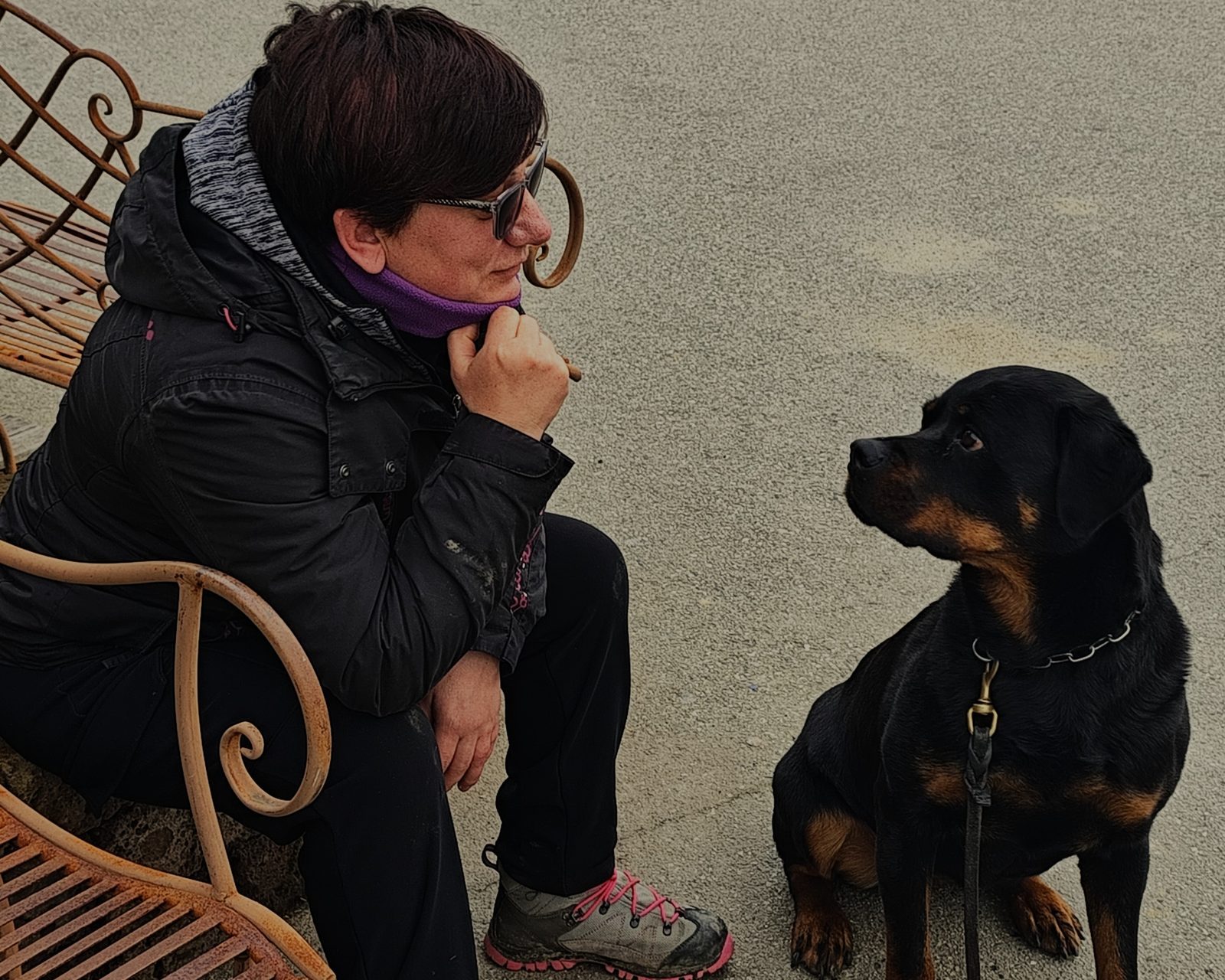 Educatrice seduta su una panchina che dialoga con il suo rottweiler